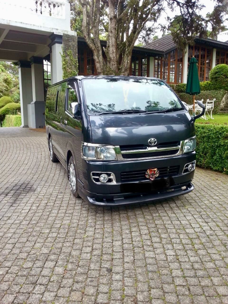 Friendly Buwi Tours driver with a happy tourist family in front of an SUV in Sri Lanka